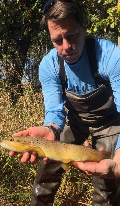 Jason Knouft, Ph.D., holds a fish while researching in an aquatic ecosystem